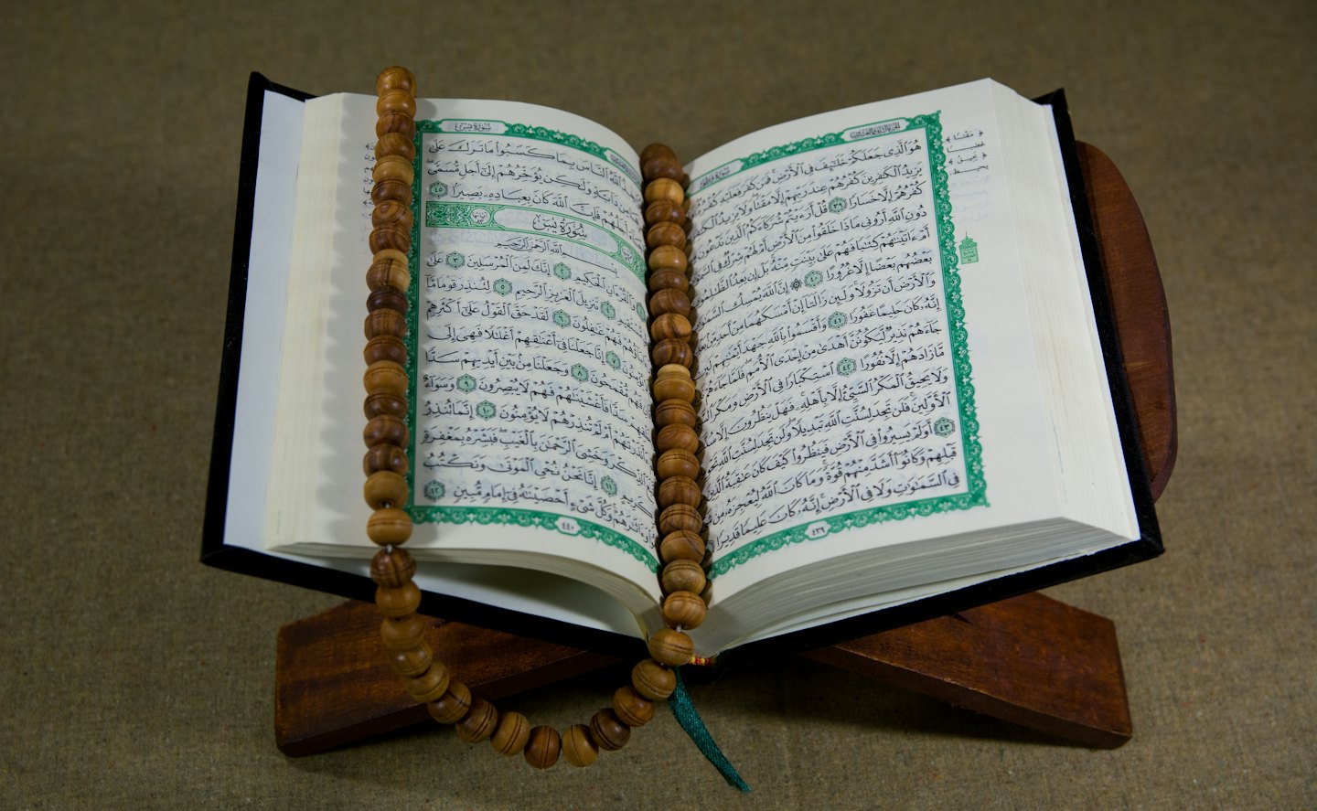 Open holy book with Arabic script and prayer beads.
